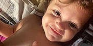 Yasmine participe au concours pour gagner de l'argent avec cette photo : arm, bed, candid, child, closeup, curly_hair, expression, face, happy, indoors, light, person, pillow, red_heart, relaxing, shadow, shirt, skin, smiling, toddler