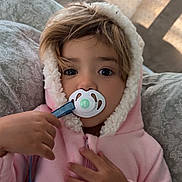 Melissa is registered to the contest to win money with this photo: toddler, child, pacifier, pink_hoodie, cute, indoors, portrait, cozy, blanket, soft_lighting, curtains, hand, face, expression, young_child, baby, warm, comfort, cushion, sleepy