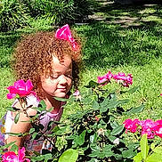 De'Winter joined the competition — help win amazing prizes! child, curly_hair, cute, flowers, garden, girl, greenery, happy, leaves, nature, outdoor, pink, pink_bow, plants, portrait, roses, smelling, summer, sunlight, young