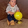 Liam Caleb Herrera is registered to the contest to win money with this photo: baby, child, couch, plaid_shirt, jeans, brown_couch, globe, toy, footwear, indoor, curious, seated, young_child, casual_clothing, soft_furniture, home, portrait, infant, looking_away, cute