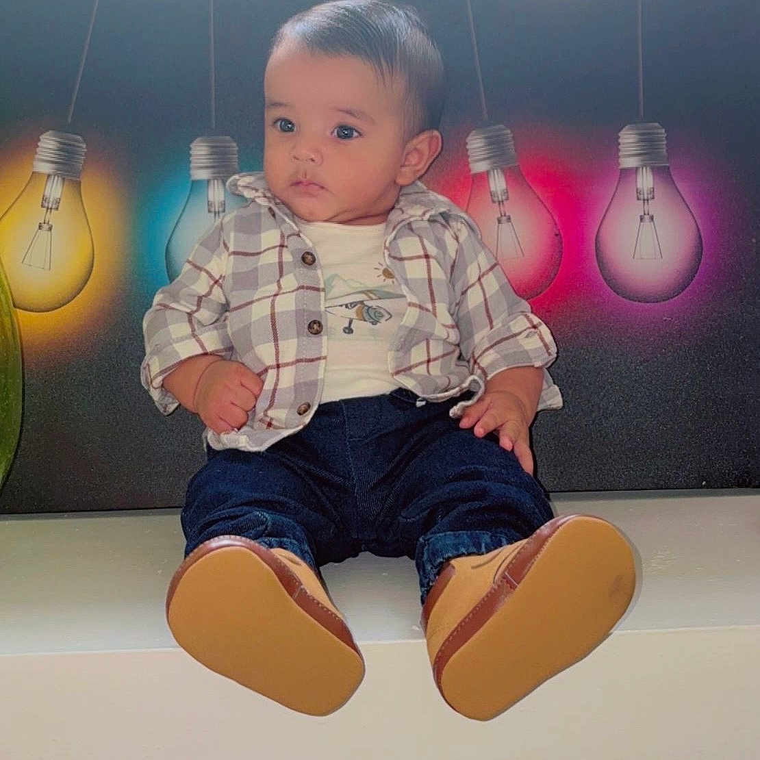 Liam Caleb Herrera joined the competition — help win amazing prizes! baby, background, casual_clothing, child, colorful_lights, cute, decor, fashion, indoor, jeans, lightbulbs, lighting, person, plaid_shirt, portrait, serious_expression, shoes, sitting, toddler, young_child