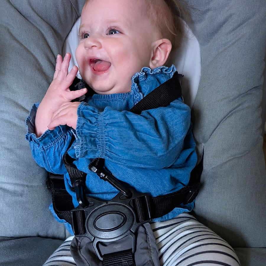 Hermione a rejoint le concours — aidez-le/la à gagner de superbes lots ! baby, baby_seat, blue_clothing, child, clapping_hands, closeup, comfort, cute, face, funny_hair, happy, indoor, infant, joy, person, safety_harness, seat, smiling, striped_leggings, toddler