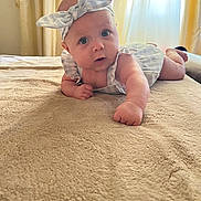Addison is registered to the contest to win money with this photo: baby, child, infant, headband, blue_eyes, blanket, bed, curtains, soft_lighting, clothing, portrait, indoors, cute, looking, lying_down, skin, expression, head, hand, toddler