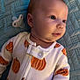 baby, infant, onesie, pumpkin_pattern, pacifier, blue_blanket, face, head, skin, clothing, sleepwear, cute, child, lying_down, soft_texture, closeup, indoors, expression, newborn, comfort