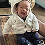 baby, child, smiling, hooded_jacket, white_jacket, bear_ears, sneakers, navy_pants, wooden_surface, indoor, happy, cute, infant, person, portrait, sitting, cozy, warm_clothing, hand, face