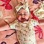 Scarlett is registered to the contest to win money with this photo: baby, infant, child, floral_headband, onesie, pink_blanket, bows, smiling, happy, cute, face, cheeks, arm, lying_down, pattern, fabric, soft, indoors, portrait, clothing