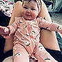 Scarlett joined the competition — help win amazing prizes! baby, child, infant, pink_onesie, headband, floral_pattern, smiling, sitting, person, indoor, legs, tattoo, blanket, chair, carpet, furniture, happy, cute, portrait, reaching