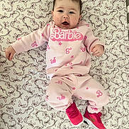 Scarlett joined the competition — help win amazing prizes! baby, infant, child, pink_clothing, barbie, sneakers, patterned_sheet, bows, lying_down, cute, face, person, indoor, apparel, footwear, happy, young_child, casual_wear, portrait, baby_girl