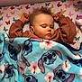 baby, sleeping, blanket, brown_sweater, butterfly_pattern, face, child, infant, bed, rest, cozy, cute, soft, comfort, nap, toddler, plush, colorful, pattern, peaceful