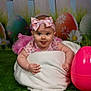 baby, child, blanket, headband, pink, easter_egg, grass, green, playful, tongue_out, cute, infant, tutu, flower_pattern, backdrop, fence, portrait, indoors, festive, smile