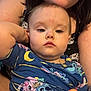 baby, child, person, adult, arm, blue_shirt, cartoon_print, indoor, holding, face, closeup, casual, comfort, expressionless, young_child, skin, hair, hand, toy, family