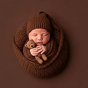 Elian is registered to the contest to win money with this photo: newborn, baby, sleeping, knitted, brown, blanket, hat, teddy_bear, crocheted, cozy, wrapped, cute, infant, portrait, soft, peaceful, child, monochrome, studio, hands