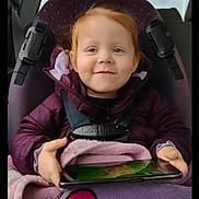 Hope joined the competition — help win amazing prizes! child, toddler, car_seat, tablet, blanket, cookie, smiling, red_hair, purple_jacket, car_interior, seatbelt, happy, baby, indoors, clothing, person, technology, cute, sitting, cozy