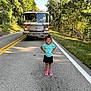 child, girl, smiling, road, fire_truck, vehicle, trees, greenery, sunlight, outdoor, nature, asphalt, sidewalk, grass, summer, casual_clothing, sandals, happy, portrait, standing