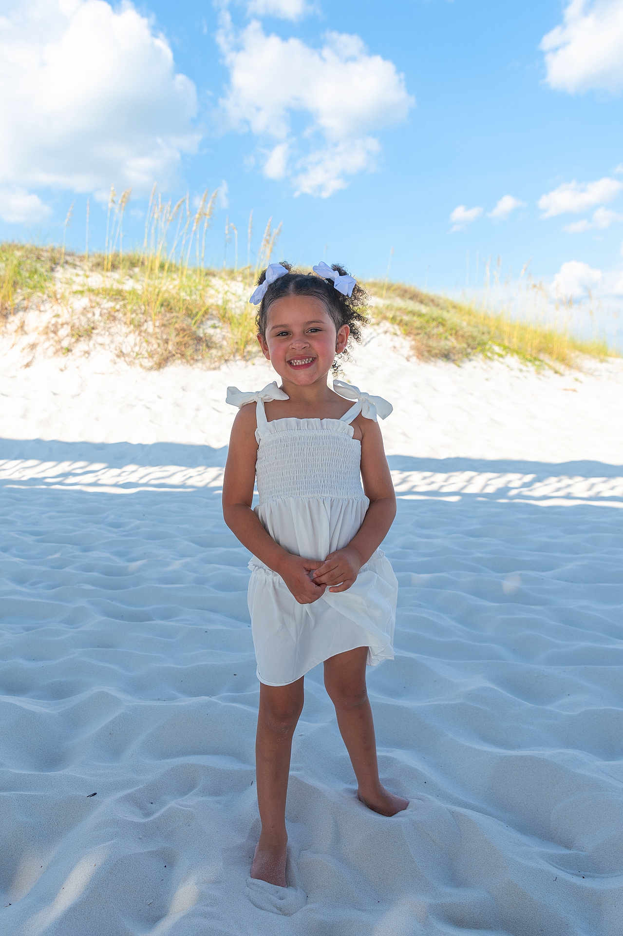 Gracelynn joined the competition — help win amazing prizes! child, girl, white_dress, sand, beach, barefoot, smile, hair_bows, blue_sky, clouds, sunlight, outdoor, nature, grass, summer, portrait, happy, vacation, cute, playful