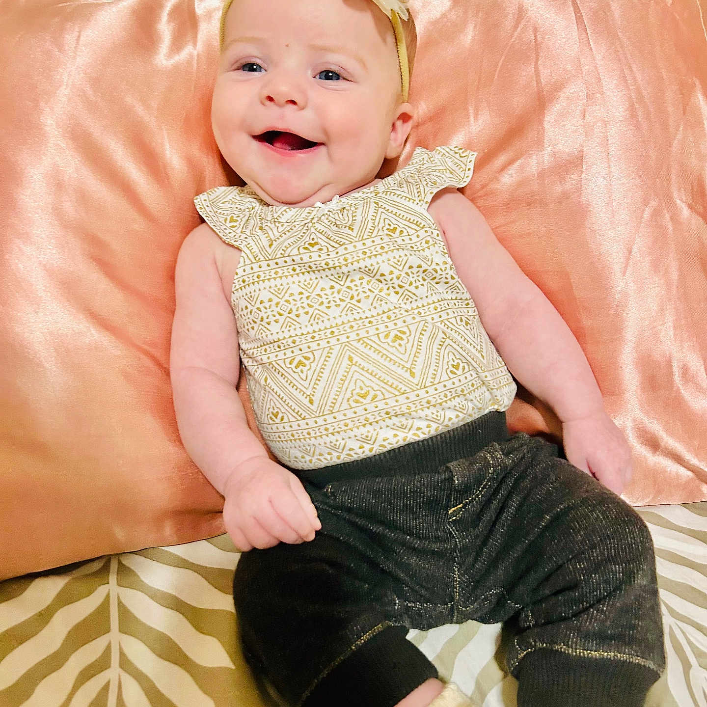 Emberly joined the competition — help win amazing prizes! baby, bedspread, child, clothing, cute, flower, happy, headband, indoor, infant, leaf_pattern, pants, patterned_top, person, pillow, portrait, relaxed, sitting, smiling, soft_lighting