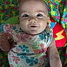 Blakely is registered to the contest to win money with this photo: baby, child, smile, face, floral_outfit, blanket, colorful, pattern, happy, infant, cute, person, skin, head, eyes, hand, sleeveless, lying_down, indoors, portrait