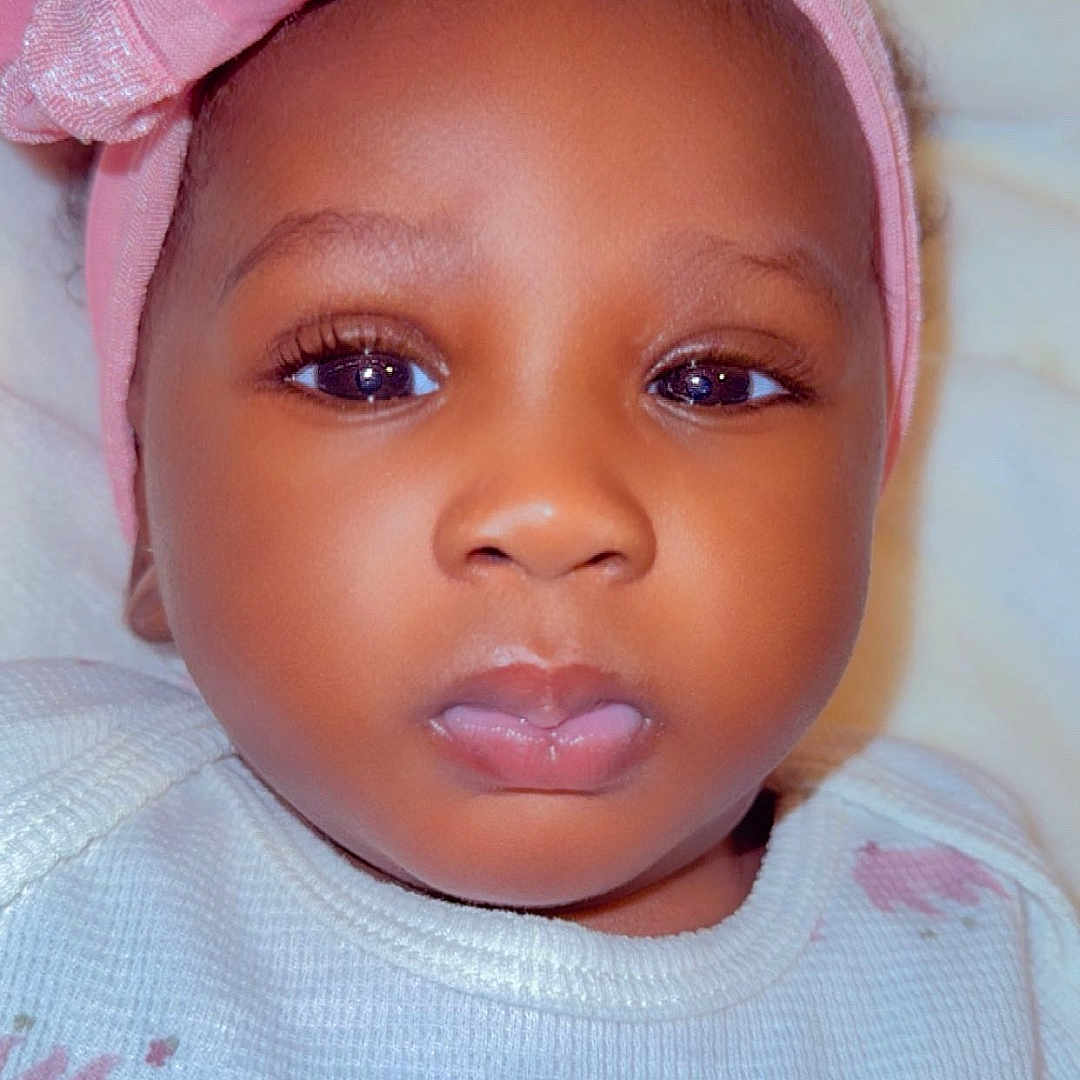 Maty joined the competition — help win amazing prizes! baby, infant, child, face, headband, pink, bow, clothing, portrait, closeup, expression, eyes, cute, young, person, soft_background, indoors, white_outfit, pattern, calm