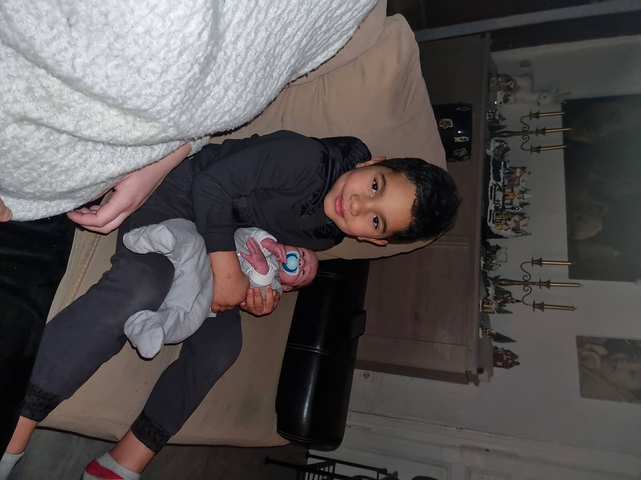 Jahyan participe au concours pour gagner de l'argent avec cette photo : baby, baby_products, baby_toddler_clothing, child, comfort, event, flooring, fun, gesture, human_leg, joint, joy, lap, person, room, sandal, sitting, smile, sock, thigh