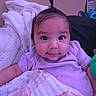 baby, child, infant, portrait, face, smiling, blanket, purple_clothing, cute, indoors, cushion, hair_ponytail, cozy, soft_toys, closeup, happy, person, baby_girl, comfort, resting