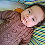 baby, child, face, eyes, sweater, knitted, brown, lying_down, striped_blanket, colorful, cute, infant, portrait, smile, cozy, soft, indoors, young, person, happy