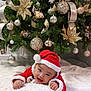 Roland Kyle joined the competition — help win amazing prizes! baby, christmas_tree, ornaments, ribbons, red_santa_hat, red_clothing, smiling, holiday, festive, decorations, white_blanket, happy, infant, indoors, celebration, greenery, sparkle, cute, seasonal, joyful