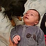 Gabriel a rejoint le concours — aidez-le/la à gagner de superbes lots ! baby, infant, dog, small_dog, blanket, onesie, hand, pet, curious, indoor, soft_fabric, face, looking_up, lying_down, cozy, animal, child, interaction, cute, young