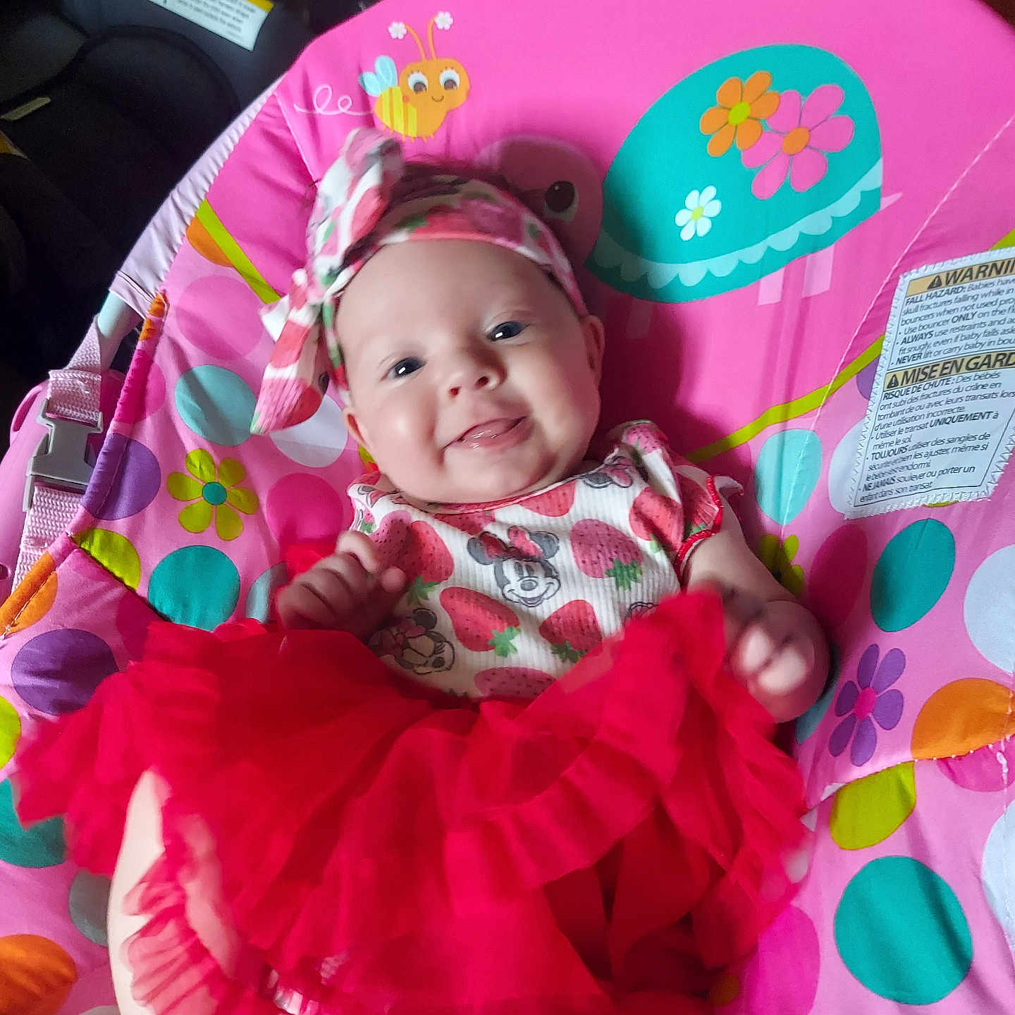Gwendolyn joined the competition — help win amazing prizes! baby, baby_chair, bee, child, colorful, cute, dress, flower, happy, headband, indoors, infant, patterned_clothing, person, playful, portrait, red_skirt, seat, smiling, turtle