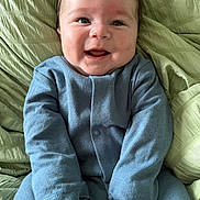 Henry is registered to the contest to win money with this photo: baby, smiling, blue_onesie, blanket, child, happy, infant, face, cute, portrait, clothing, lying_down, cozy, soft_texture, young_child, indoor, closeup, person, head, cheerful