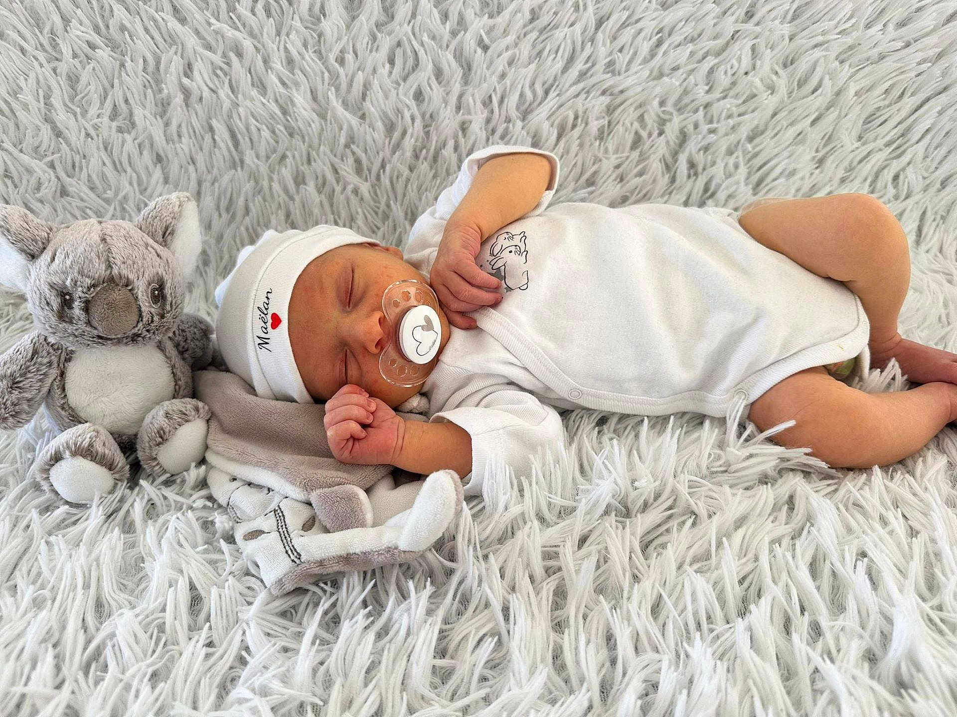 Maëlan a rejoint le concours — aidez-le/la à gagner de superbes lots ! newborn, baby, sleeping, pacifier, plush_toy, koala, white_clothing, hat, blanket, soft_texture, infant, resting, cute, peaceful, indoor, child, tiny_hand, cozy, portrait, babywear