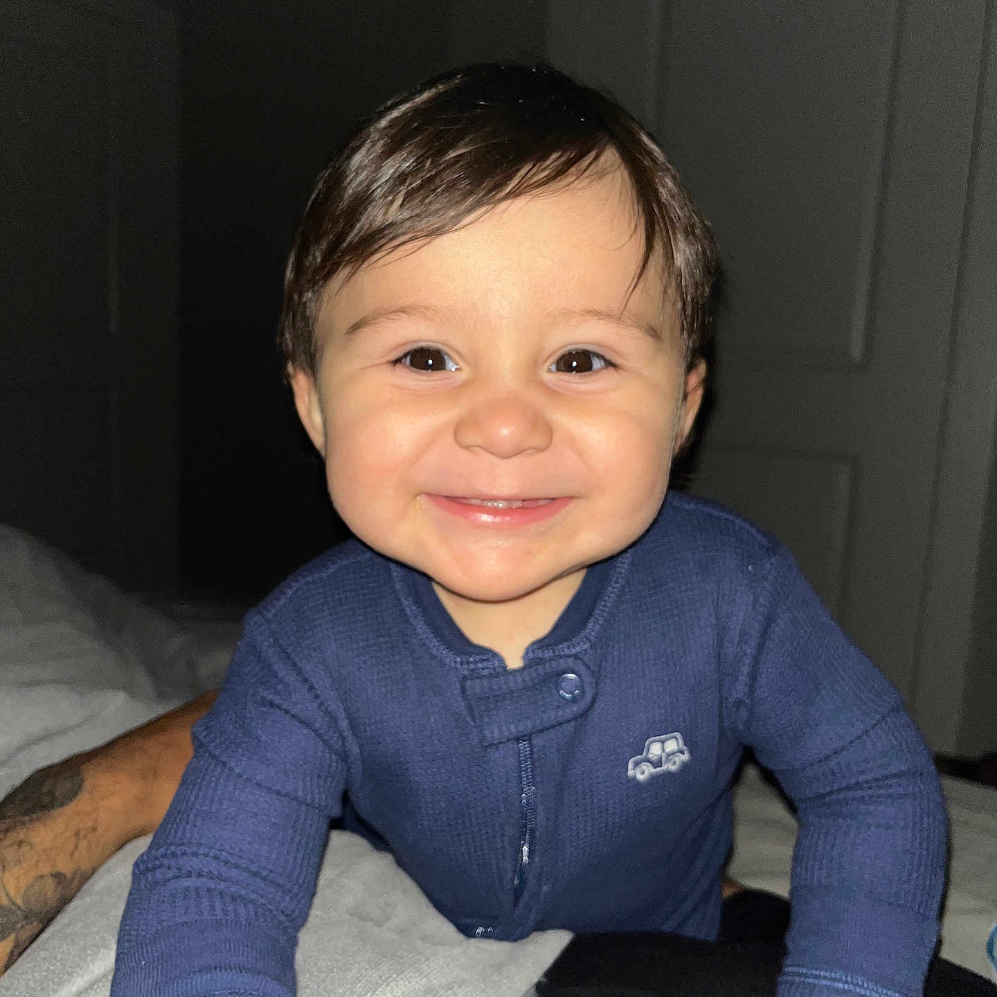 Kiiian is registered to the contest to win money with this photo: baby, blue_clothing, car_emblem, child, crawling, cute, dark_background, eyes, face, hands, happy, indoor, infant, lighting, person, portrait, sleepwear, smiling, toddler, young_child