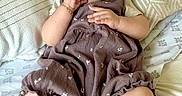 Aria is registered to the contest to win money with this photo: apparel, baby, bed, blanket, child, clothing, comfortable, cozy, cute, expression, face, hand, headband, indoors, infant, person, pillow, portrait, sitting, socks