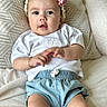 baby, child, infant, headband, flower, cushion, white_shirt, denim_shorts, bracelet, indoor, portrait, cute, smiling, person, skin, hand, legs, seated, cozy, soft_fabric