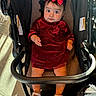 baby, child, stroller, red_dress, headband, bow, sandals, footwear, curious, indoors, floor_tiles, sunlight, shadow, person, seated, infant, cute, fashion, clothing, expression