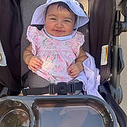 Iliany Diaz joined the competition — help win amazing prizes! baby, child, smiling, stroller, hat, pink_clothing, floral_pattern, sunlight, happy, cute, infant, seatbelt, outdoor, person, portrait, baby_clothes, headwear, baby_girl, seat, daylight