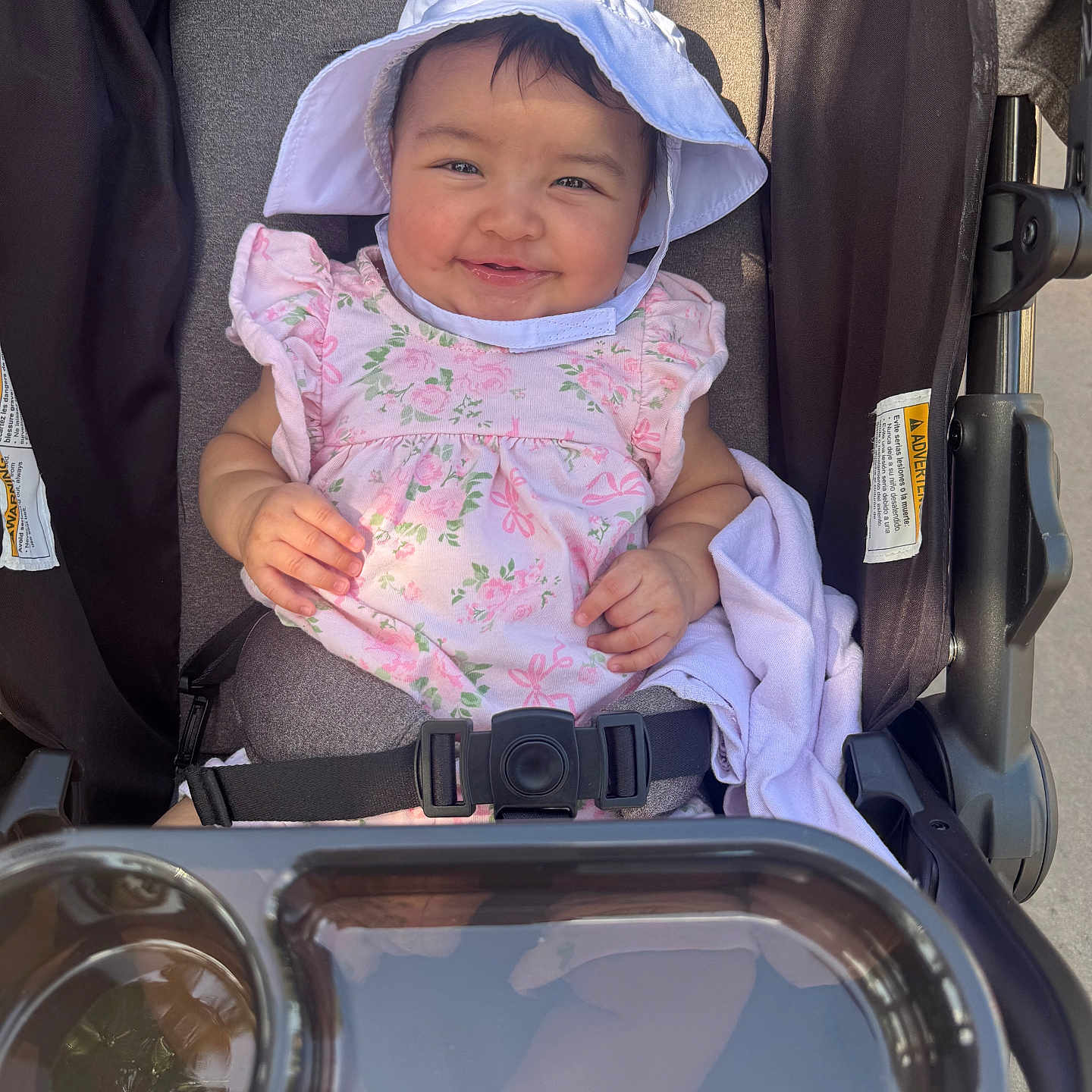 Iliany Diaz joined the competition — help win amazing prizes! baby, child, smiling, stroller, hat, pink_clothing, floral_pattern, sunlight, happy, cute, infant, seatbelt, outdoor, person, portrait, baby_clothes, headwear, baby_girl, seat, daylight