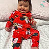baby, infant, child, red_clothing, minnie_mouse, headband, smile, bed, pillow, blanket, cute, indoors, person, sitting, happy, face, chubby_cheeks, patterned_clothing, soft_lighting, portrait