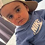 toddler, child, face, cap, hat, hoodie, blue_clothing, nike, indoor, portrait, curious, young_child, person, apparel, headwear, clothing, looking, casual, seated, expression