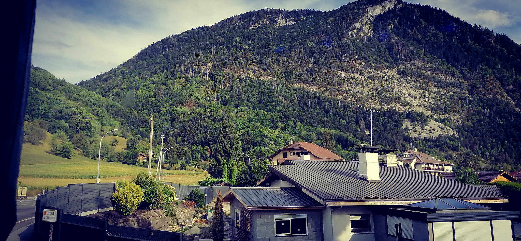 Peppa participe au concours pour gagner de l'argent avec cette photo : architecture, biome, building, city, cloud, highland, house, landscape, mountain, mountain_range, mountainous_landforms, natural_landscape, plant, residential_area, rural_area, sky, slope, tree, vegetation, window