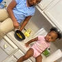child, toddler, kitchen, counter, bowl, spoon, eggs, cup, paper_towel, cabinet, stove, cooking, clothing, sitting, hair, person, indoor, appliance, young_child, family