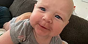 Callie joined the competition — help win amazing prizes! baby, child, infant, face, eyes, smile, closeup, indoor, couch, person, tshirt, skin, head, expression, cute, young, lying, human, apparel, background