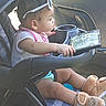 baby, child, car_seat, car, sunglasses, infant, sitting, dashboard, vehicle, portrait, side_profile, reaching, pink_clothing, white_shirt, plush_boots, toy, indoor, daylight, family, road_trip
