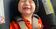 Matthias is registered to the contest to win money with this photo: child, toddler, car_seat, smiling, happy, beanie, orange_shirt, seatbelt, car_interior, safety, cute, baby, face, headwear, portrait, transportation, travel, young_child, sitting, daylight
