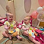 baby, toys, balloons, birthday, present, number_one_balloon, crown_balloon, carpet, child, indoor, gift_wrap, pink, purple, smiling, sitting, onesie, playful, celebration, doll, happy