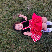 Shama is registered to the contest to win money with this photo: casual, child, curly_hair, cute, dress, fun, grass, happy, lying_down, nature, outdoor, person, playful, polka_dots, purple_shoes, red_dress, smiling, sneakers, toddler, young_child