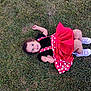 casual, child, curly_hair, cute, dress, fun, grass, happy, lying_down, nature, outdoor, person, playful, polka_dots, purple_shoes, red_dress, smiling, sneakers, toddler, young_child