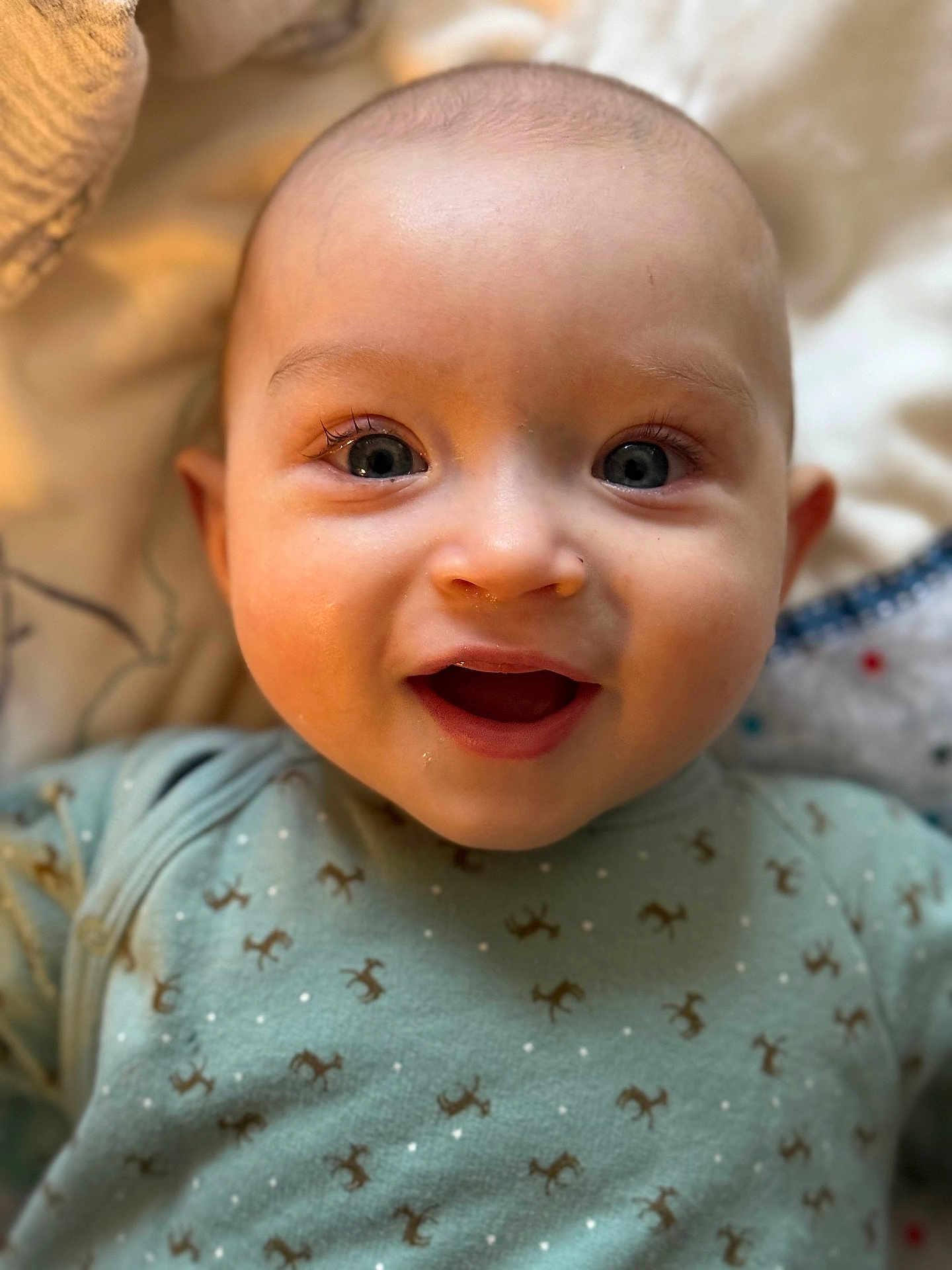 Jules participe au concours pour gagner de l'argent avec cette photo : baby, infant, smile, face, eyes, onesie, green_clothing, blanket, closeup, happy, child, cute, skin, head, person, newborn, lying_down, indoors, soft_light, expression