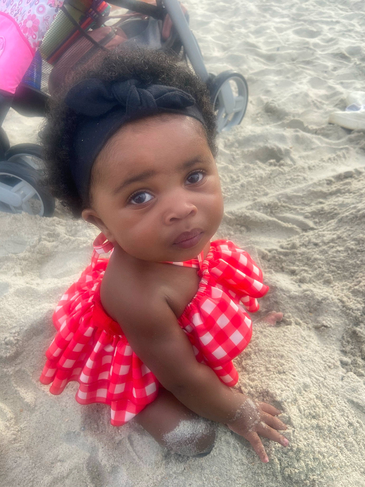 Emerald is registered to the contest to win money with this photo: beach, black_hair, carmine, child, chin, dress, eye, eyelash, fashion_accessory, fun, hair, happy, headpiece, human_leg, lip, pattern, people, person, pink, skin