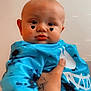 Asher is registered to the contest to win money with this photo: baby, child, blue_shirt, tie_dye, tattoo, hand, face, heart_filter, cute, expression, portrait, indoor, skin, person, holding, clothing, smile, young_child, closeup, eyes