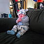 baby, child, sitting, couch, indoor, hat, pajamas, cartoon_characters, clothing, furniture, person, toddler, smile, face, footwear, socks, exercise_equipment, background, home, relaxing